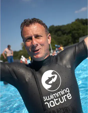 Founder Eduardo Ferré, wearing a Swimming Nature wetsuit top, smiles beside a pool.