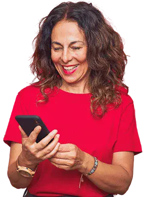 Smiling customer in a red blouse taps on her smartphone against a light background.