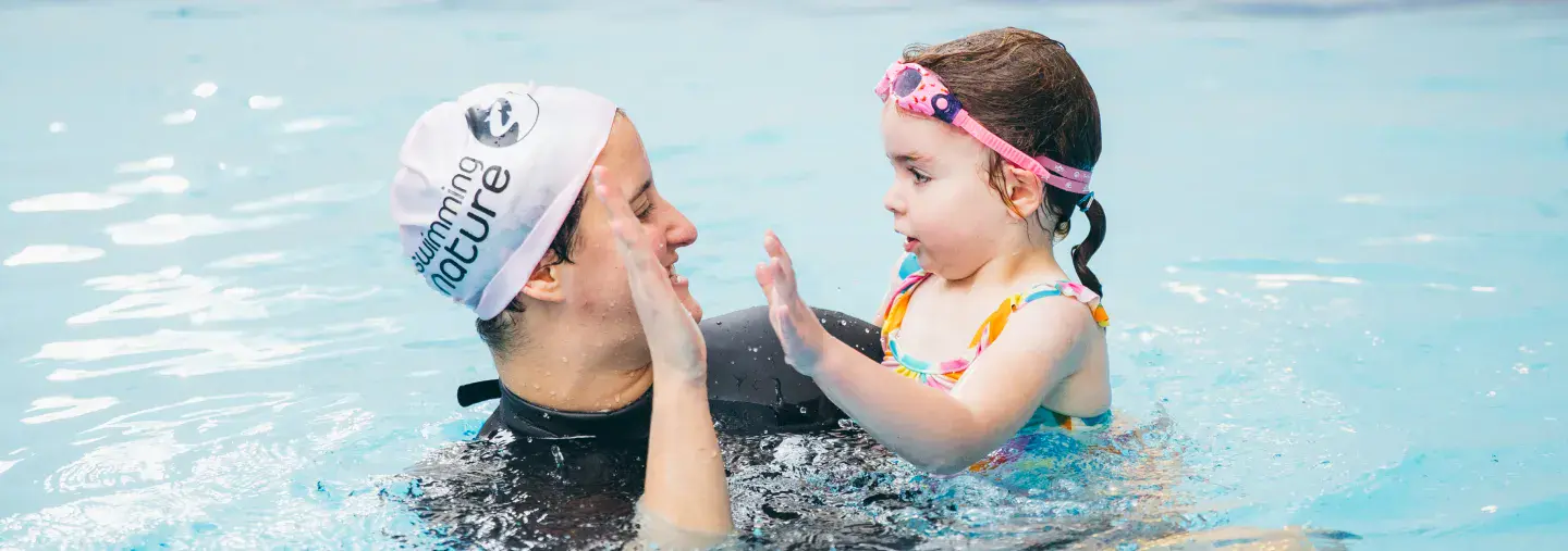 Children and instructor smiling while swimming in a pool